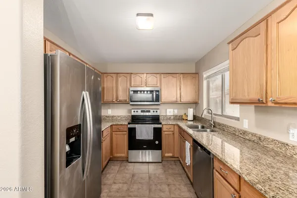 a kitchen with stainless steel appliances granite countertop a refrigerator a stove and a sink