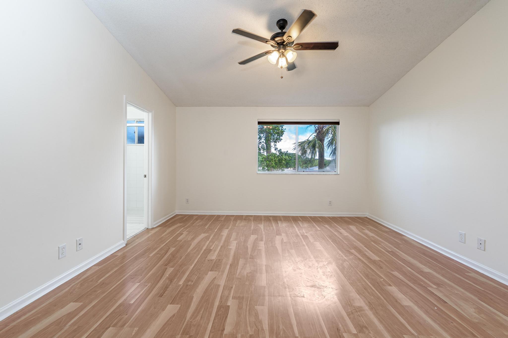 8271 Vía Serena Boca Raton, FL 33433 - Photo 17 of 33 an empty room with wooden floor chandelier fan and windows