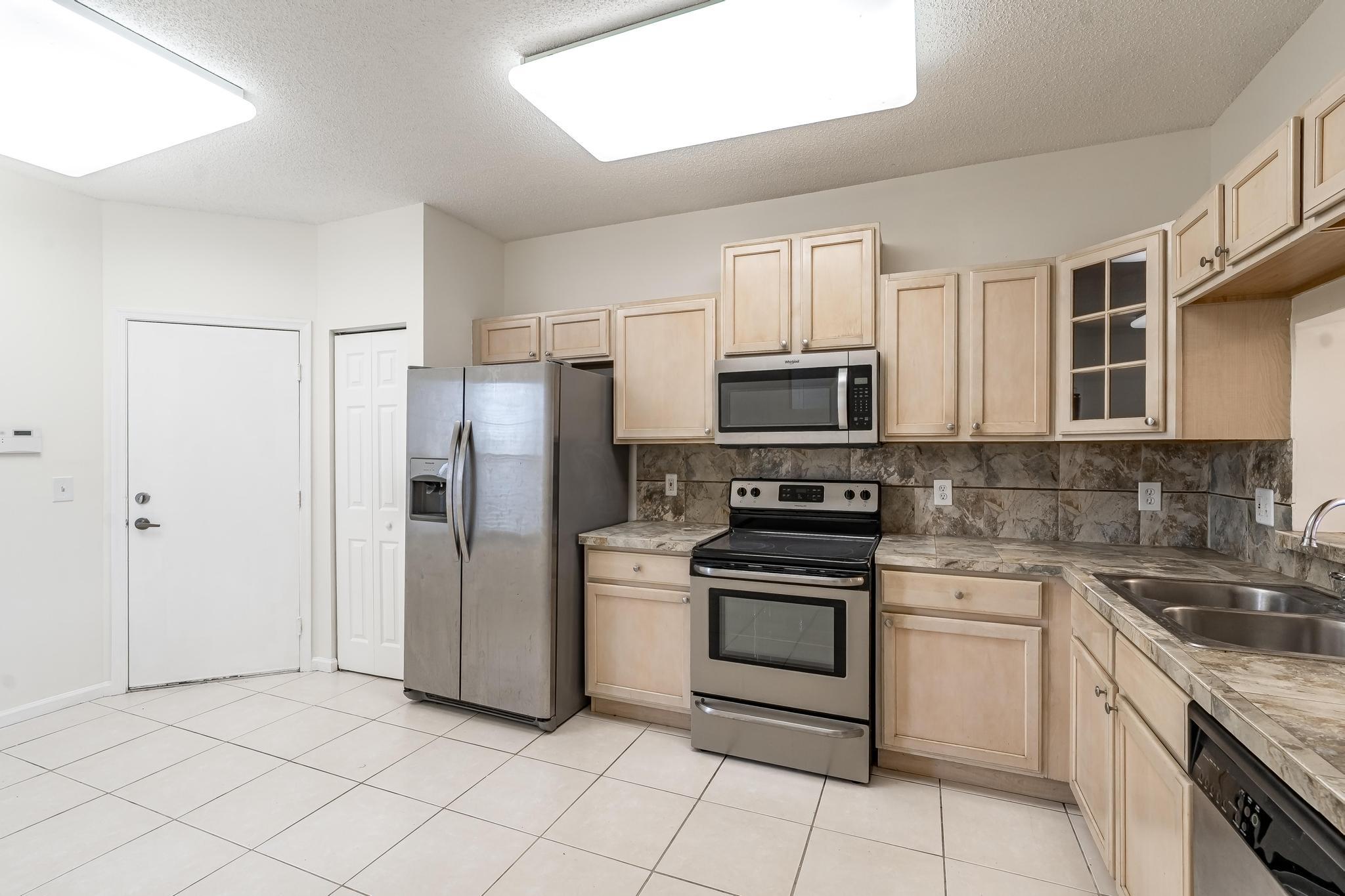 8271 Vía Serena Boca Raton, FL 33433 - Photo 7 of 33 a kitchen with white cabinets stainless steel appliances and a sink