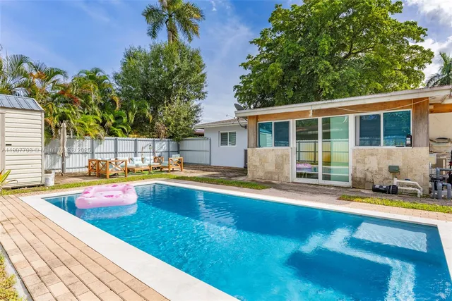 a view of swimming pool with lounge chair and dinning table under an umbrella