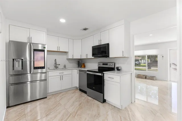 a kitchen with white cabinets and stainless steel appliances