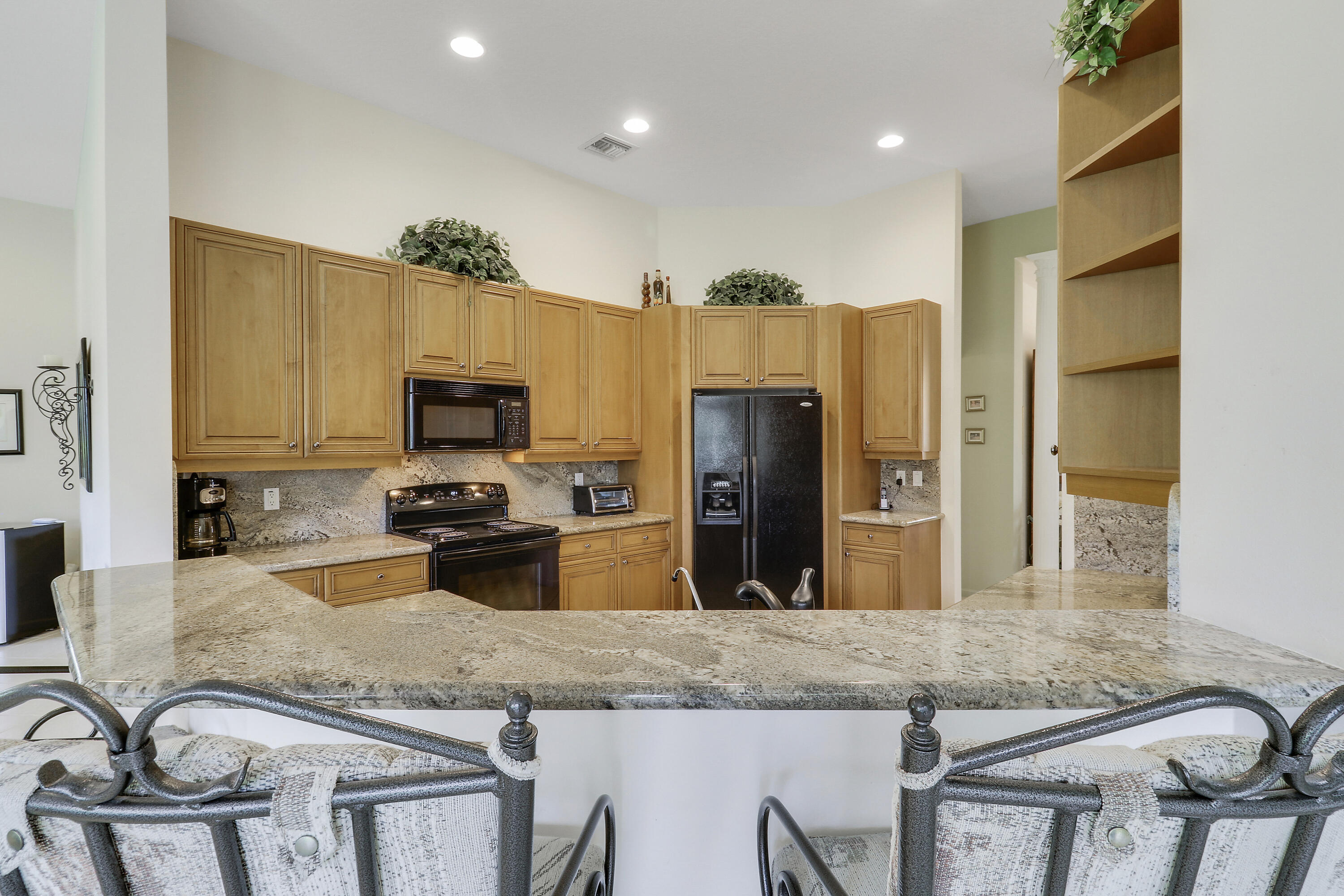 6565 Garde Road Boynton Beach, FL 33472 - Photo 12 of 54 a kitchen with granite countertop kitchen island stainless steel appliances a sink refrigerator stove and microwave
