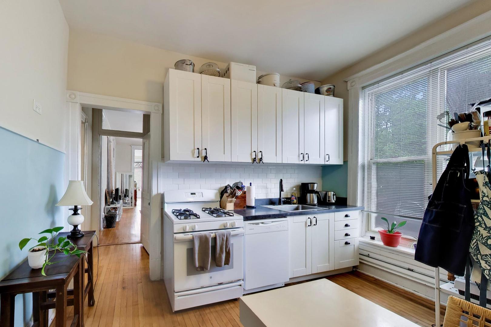 2701 West Haddon Avenue Chicago, IL 60622 - Photo 4 of 22 a kitchen with a sink dishwasher and white cabinets with wooden floor