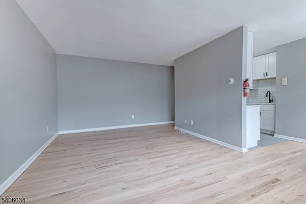 a view of empty room with wooden floor and a refrigerator
