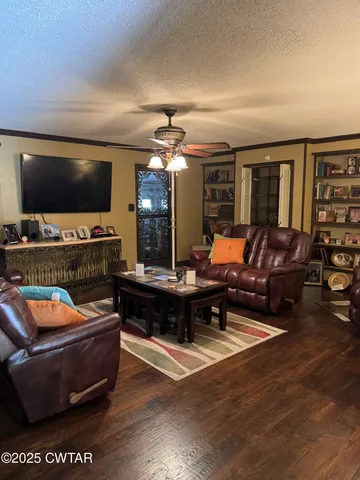 a living room with furniture a flat screen tv and floor to ceiling window