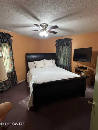 a bed sitting in a bedroom next to a window with pc on the table