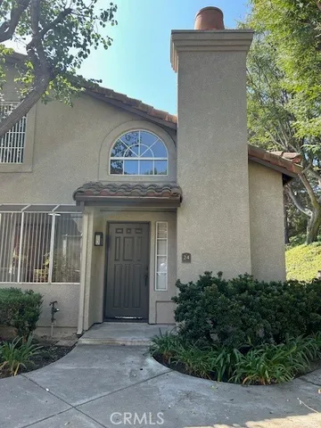 a view of a house with a small yard plants and large tree
