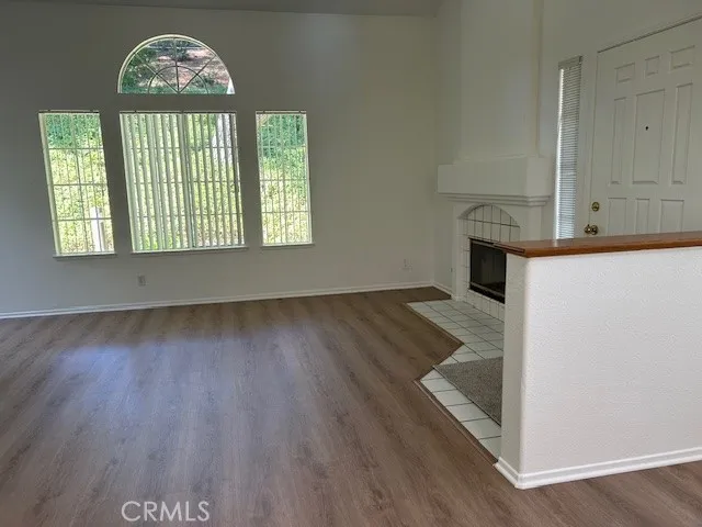 an empty room with wooden floor a fireplace and windows