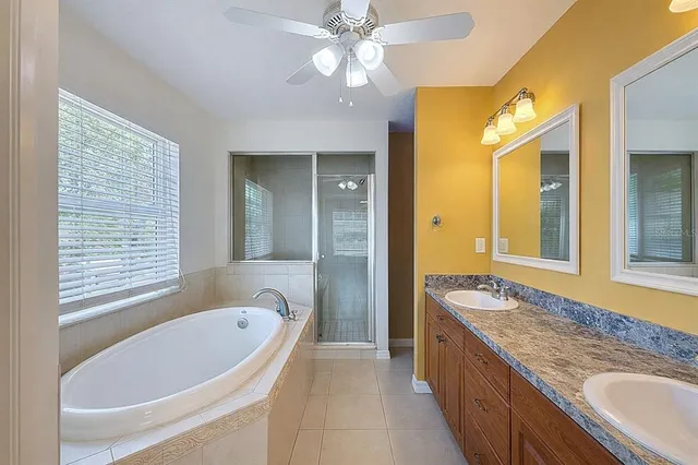 a bathroom with a granite countertop tub sink shower and mirror