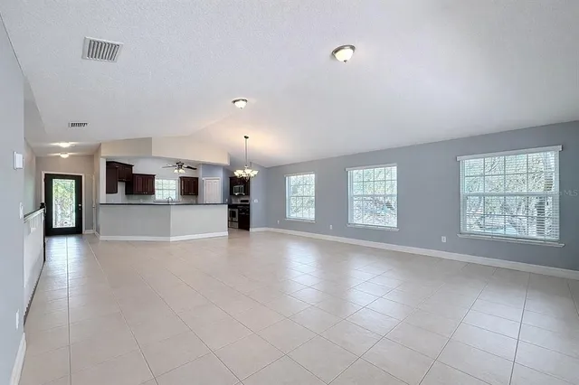 a view of an empty room with a window and kitchen view
