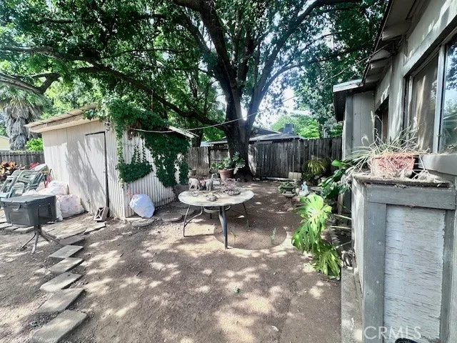 a view of a backyard with table and chairs potted plants and wooden fence