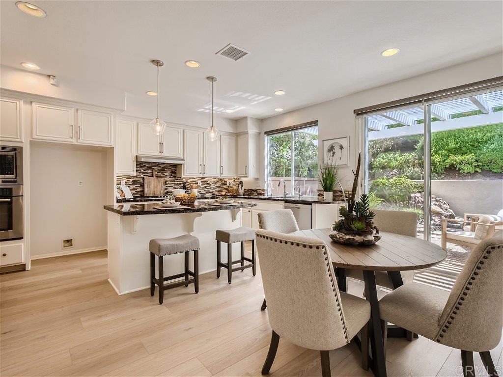 6562 Windflower Drive Carlsbad, CA 92011 - Photo 11 of 28 a kitchen with kitchen island a dining table and chairs