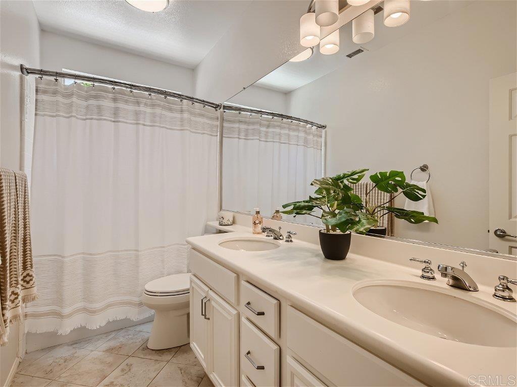 6562 Windflower Drive Carlsbad, CA 92011 - Photo 22 of 28 a bathroom with a granite countertop sink a toilet and mirror