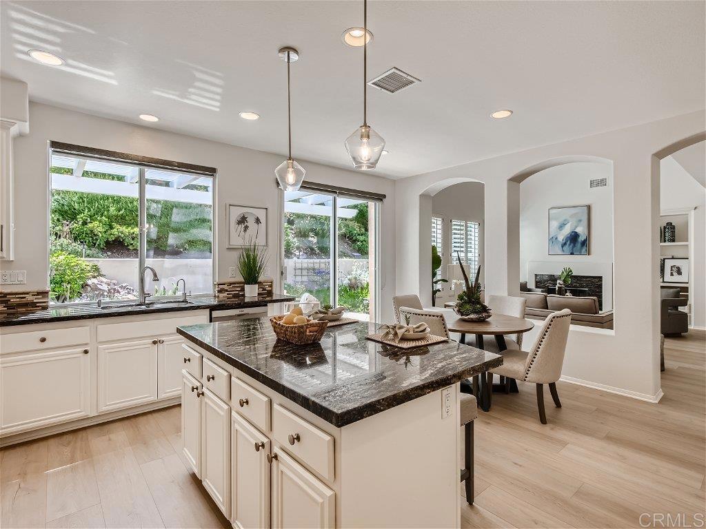 6562 Windflower Drive Carlsbad, CA 92011 - Photo 9 of 28 a kitchen with granite countertop a stove a sink a dining table and chairs with wooden floor