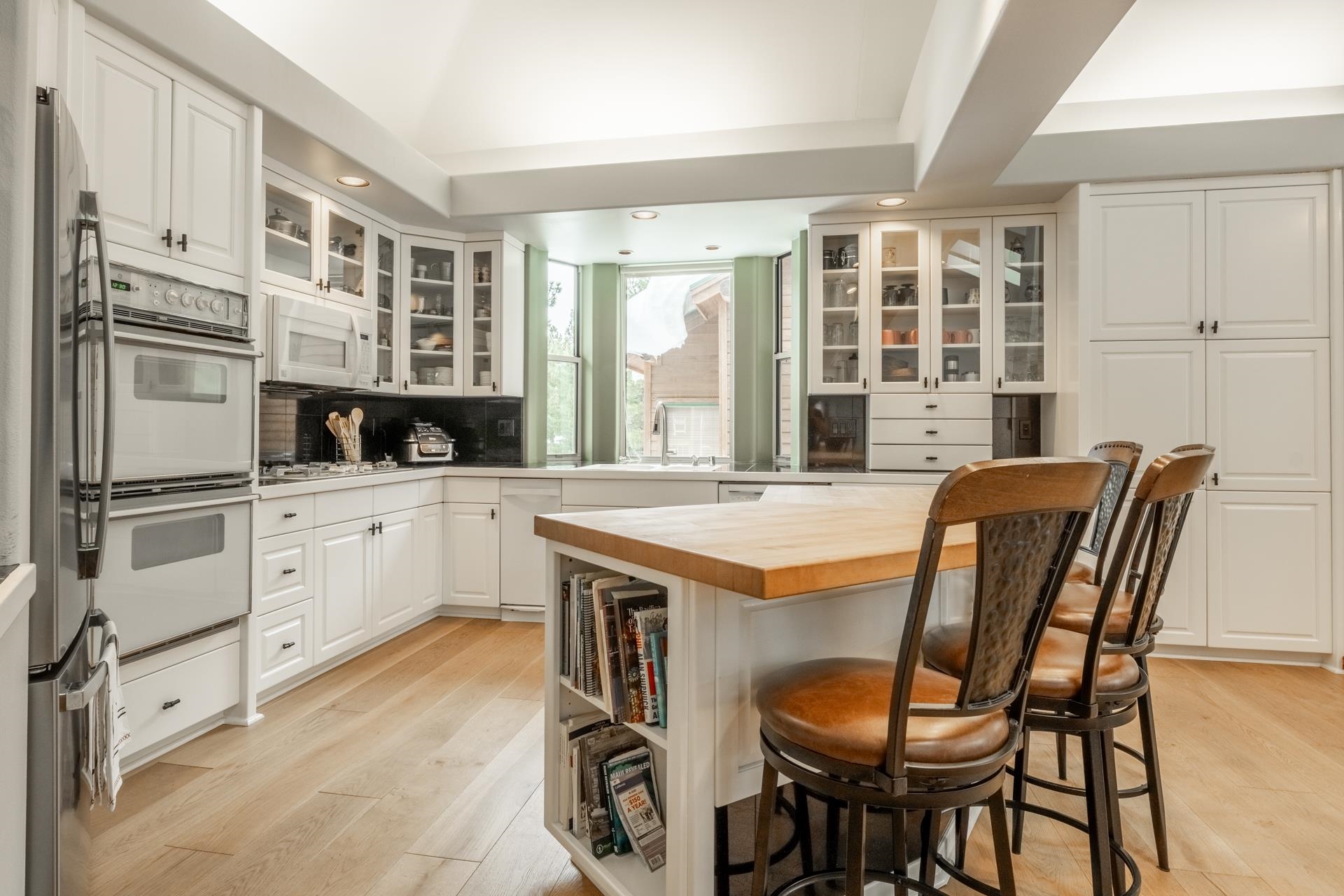244 Ridge Way Mammoth Lakes, CA 93546 - Photo 18 of 49 Kitchen featuring a breakfast bar area, wood counters, glass insert cabinets, stainless steel appliances, and light wood-style flooring