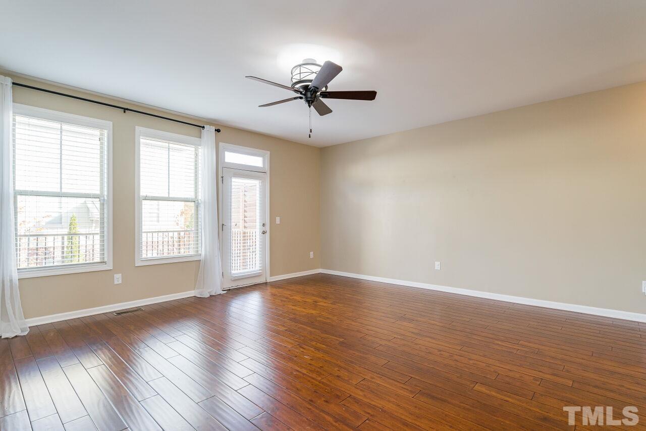 1323 Rodessa Run Raleigh, NC 27607 - Photo 12 of 29 an empty room with wooden floor chandelier fan and windows
