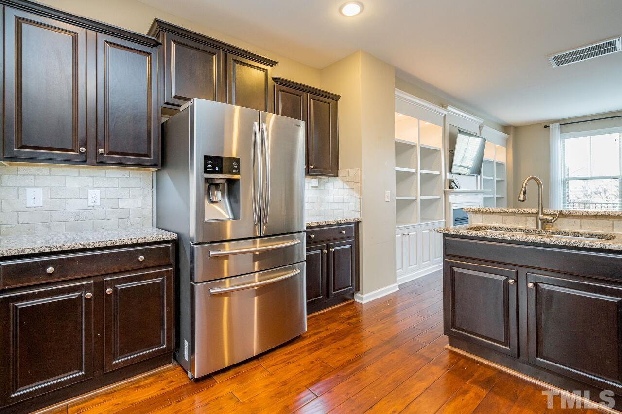 1323 Rodessa Run Raleigh, NC 27607 - Photo 17 of 29 a kitchen with granite countertop wooden floors stainless steel appliances and a window
