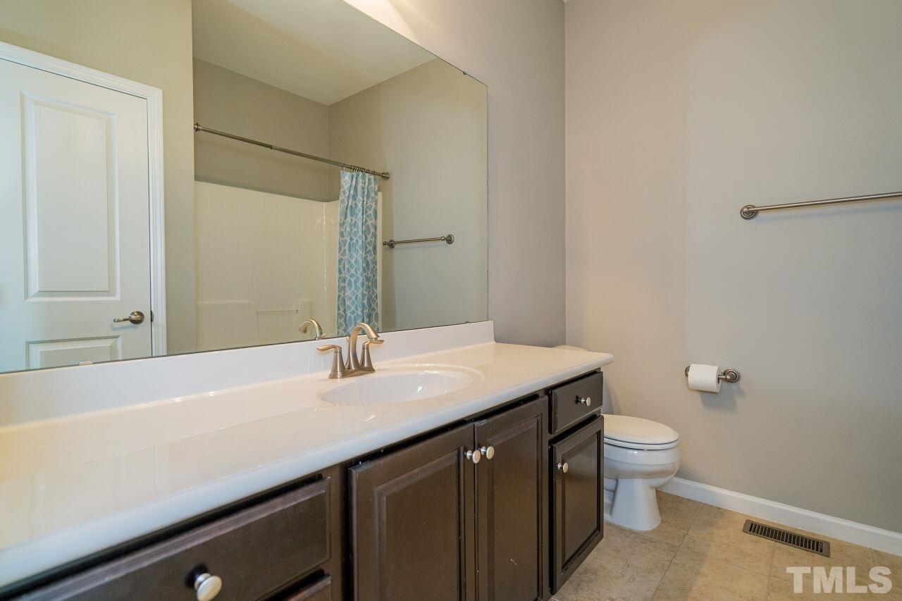 1323 Rodessa Run Raleigh, NC 27607 - Photo 27 of 29 a bathroom with a granite countertop sink a toilet and a mirror