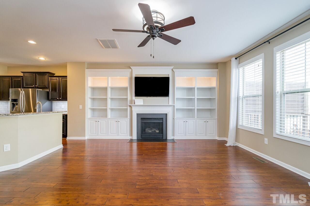 1323 Rodessa Run Raleigh, NC 27607 - Photo 9 of 29 a view of a livingroom with a flat screen tv wooden floor and a ceiling fan