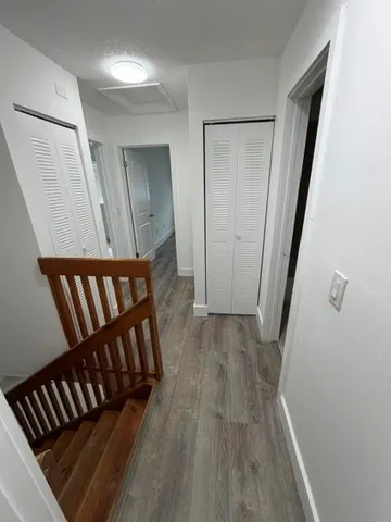 a view of a hallway with wooden floor and staircase