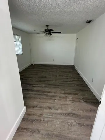 a view of an empty room with wooden floor and cabinet
