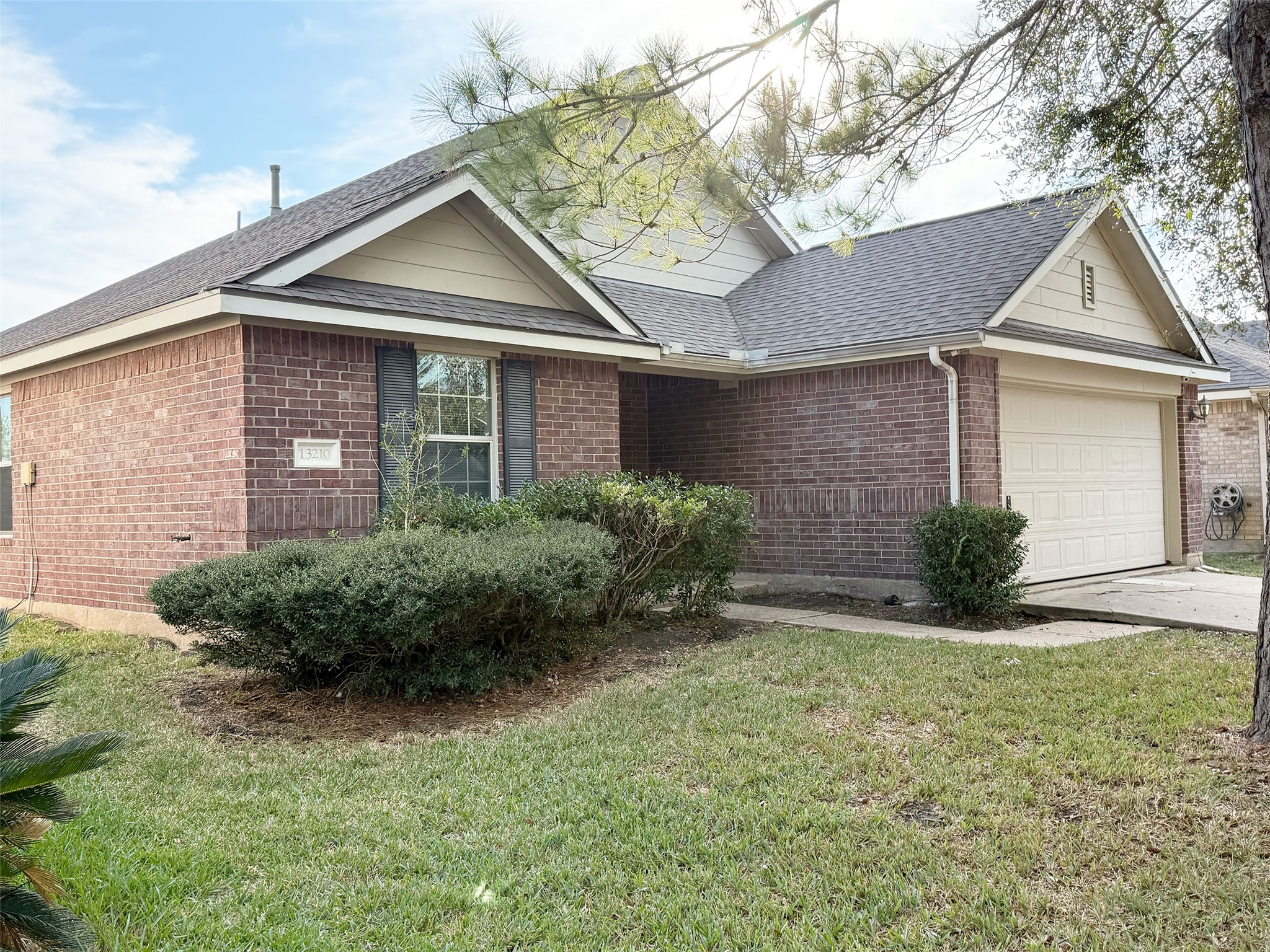 Charming brick single-story home with a well-maintained front yard, mature shrubs, and a two-car garage. Features a gabled roof and inviting entryway, perfect for a cozy, suburban lifestyle.