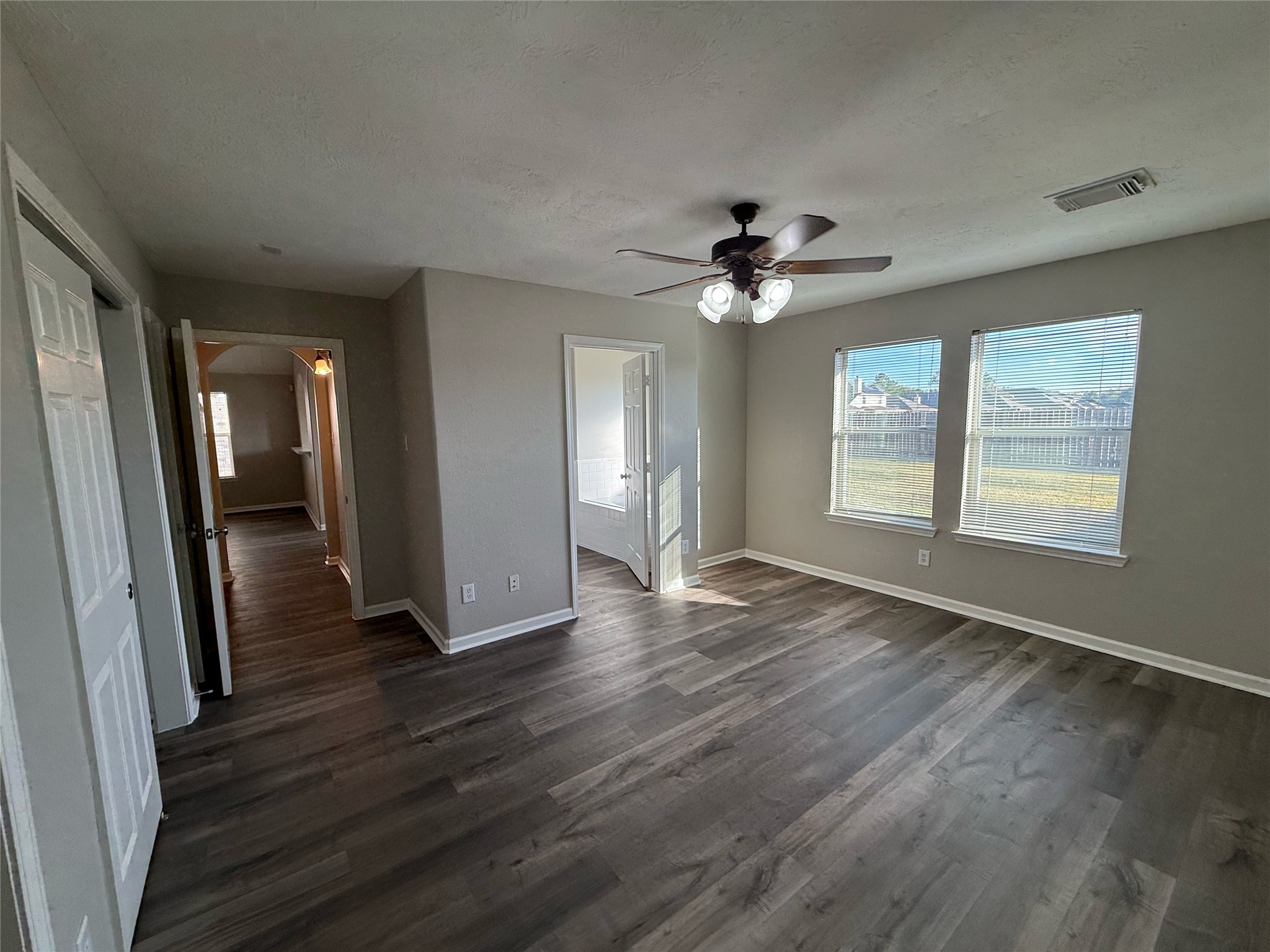 13210 Barton Meadow Lane Rosharon, TX 77583 - Photo 11 of 21 Bright, spacious room with large windows, laminate flooring, and a ceiling fan. It leads to a hallway and another well-lit area, perfect for versatile use.