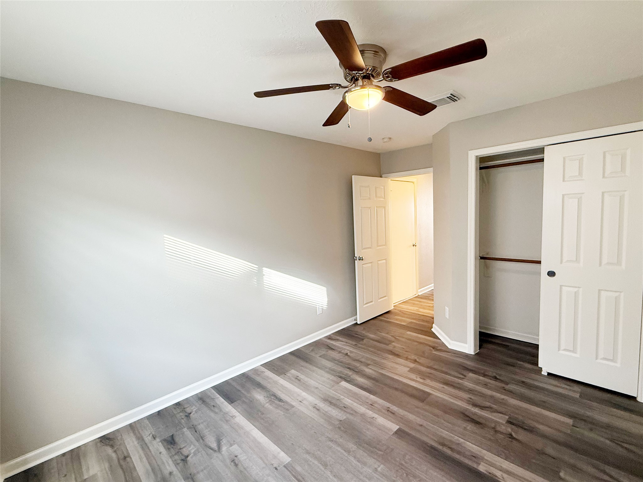 13210 Barton Meadow Lane Rosharon, TX 77583 - Photo 17 of 21 This room features sleek laminate flooring, neutral walls, a ceiling fan, and ample natural light. It includes a closet with sliding doors and an adjoining hallway entrance.
