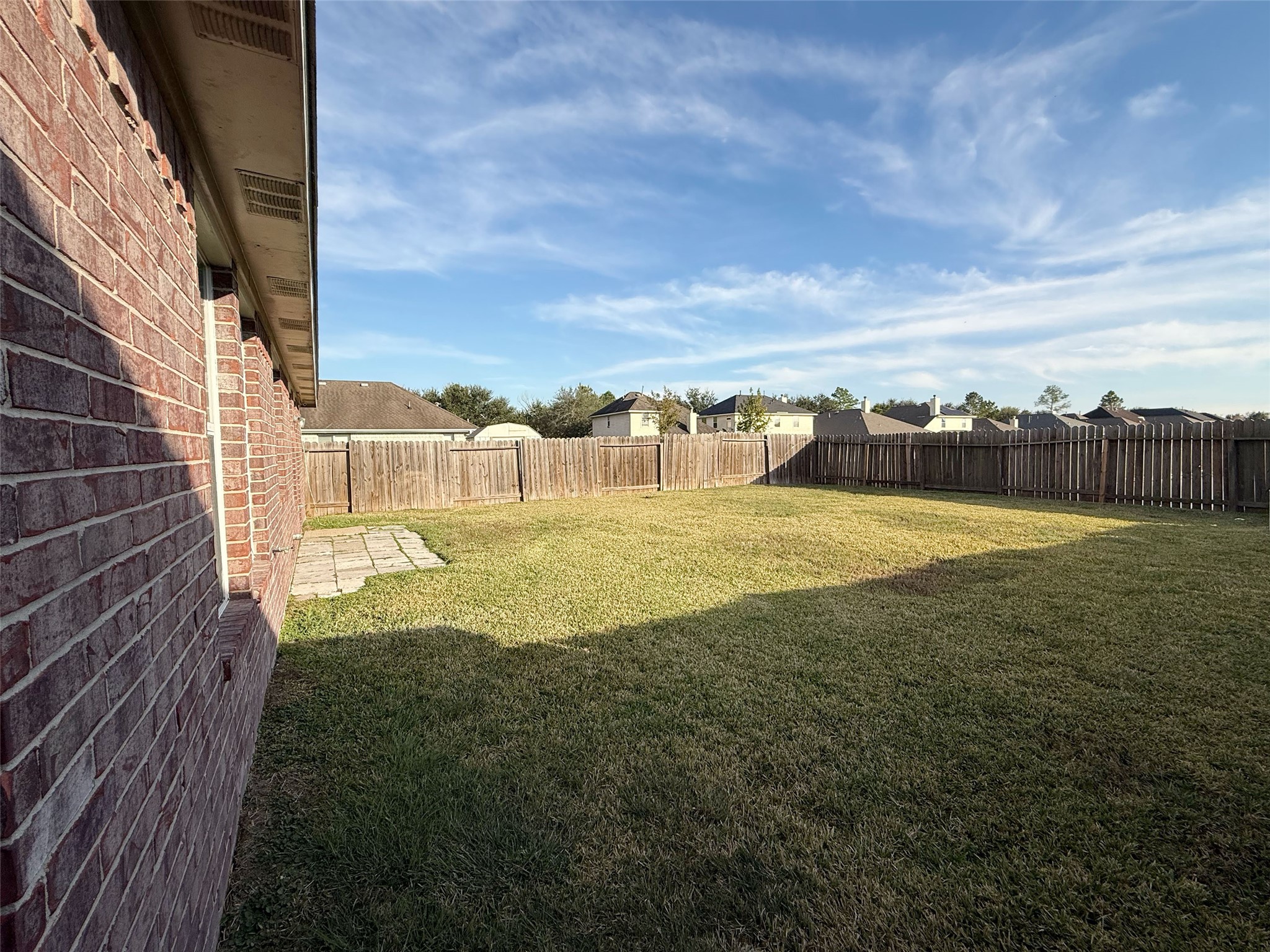 13210 Barton Meadow Lane Rosharon, TX 77583 - Photo 20 of 21 Spacious fenced backyard with a well-maintained lawn, brick exterior, and a small patio area, ideal for outdoor activities and privacy.