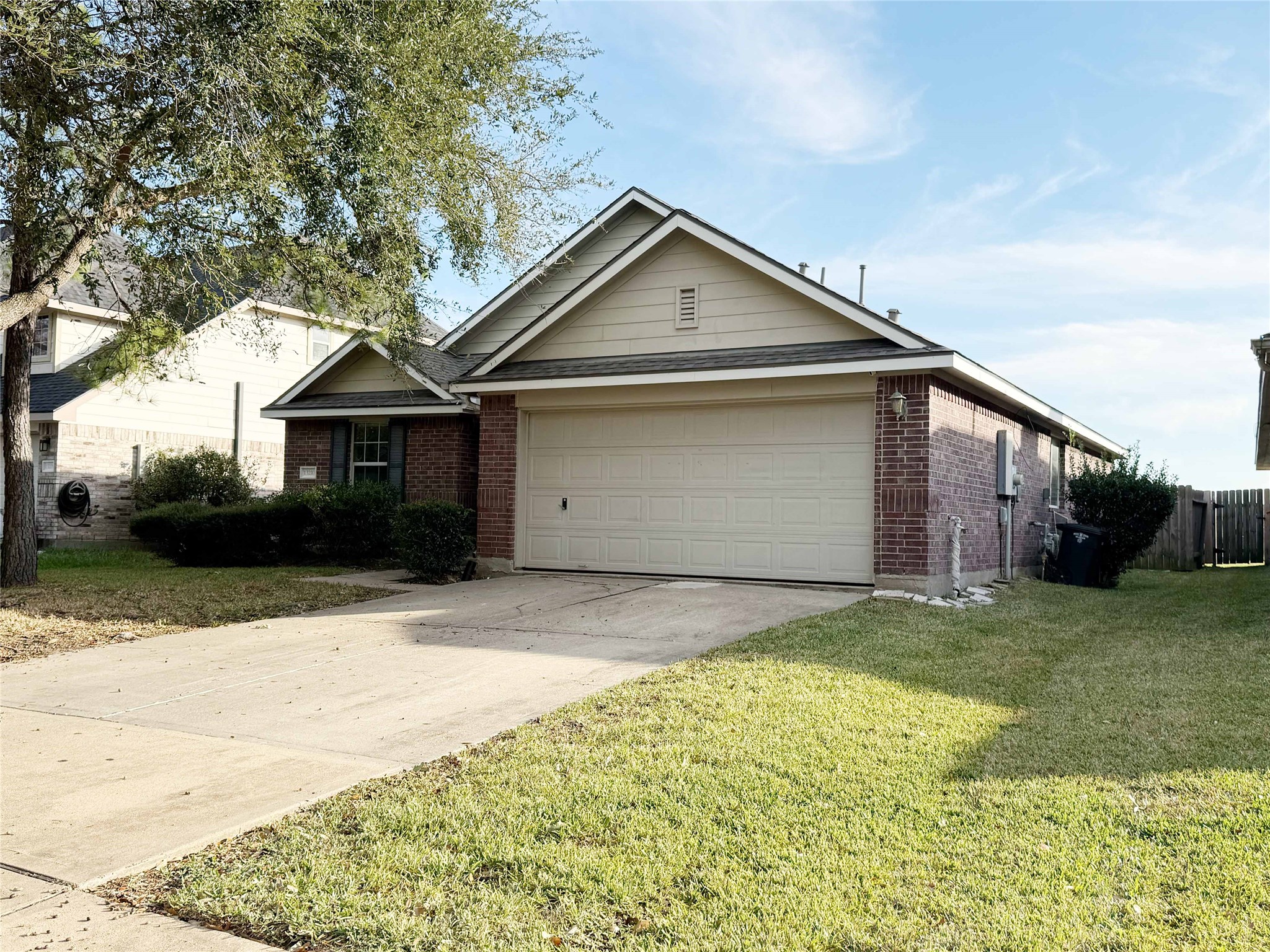 13210 Barton Meadow Lane Rosharon, TX 77583 - Photo 2 of 21 This is a single-story brick home with a two-car garage, a well-maintained lawn, and a driveway. It features a gabled roof and a small front garden with shrubs and a tree, providing a welcoming curb appeal in a suburban setting.