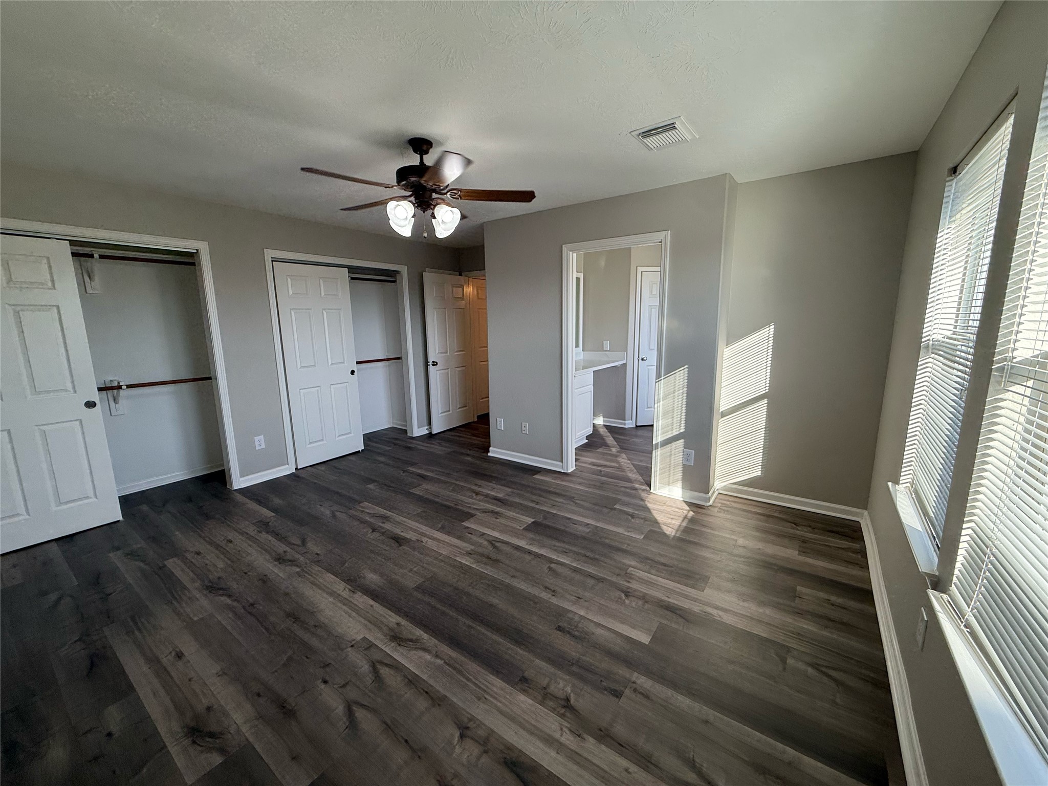 13210 Barton Meadow Lane Rosharon, TX 77583 - Photo 10 of 21 Bright and spacious bedroom with dark wood flooring, a ceiling fan, multiple closets, and plenty of natural light from large windows.