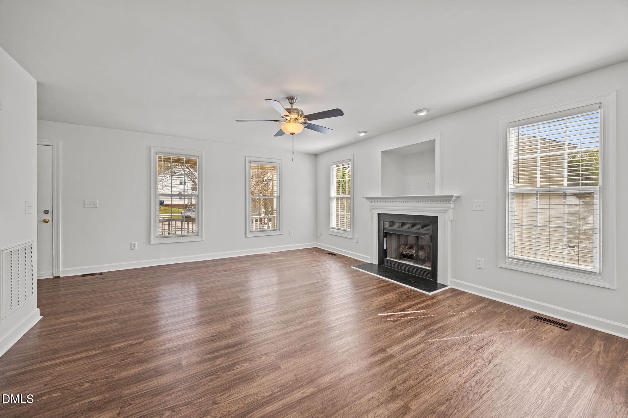 9220 Pennythorne Court Raleigh, NC 27615 - Photo 13 of 49 an empty room with windows a fireplace and wooden floor