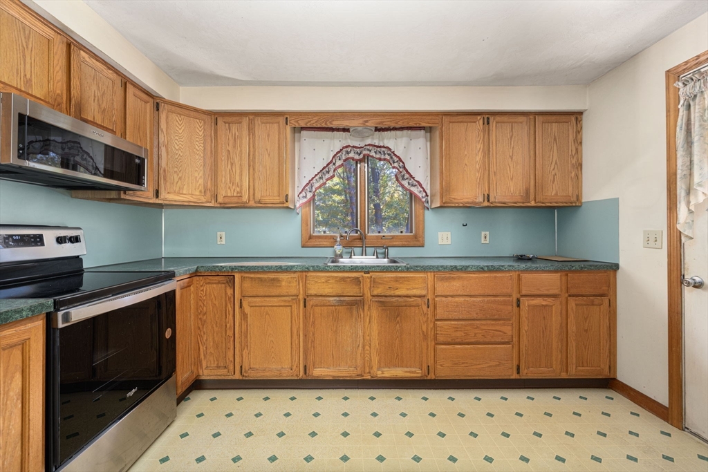 40 Union Street Blackstone, MA 01504 - Photo 32 of 40 a kitchen with granite countertop a stove a sink and a microwave