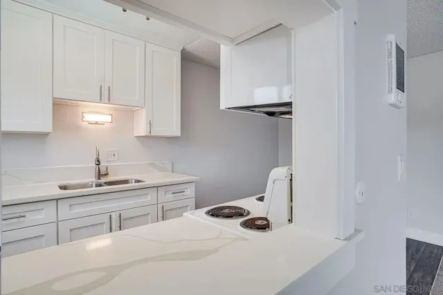 a kitchen with a stove a refrigerator and a white cabinets