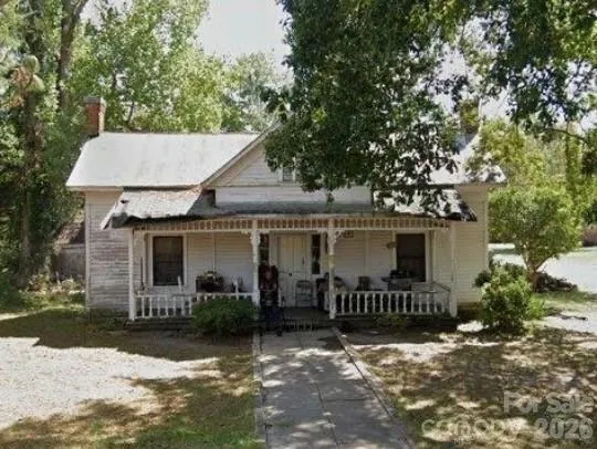 a view of a house with a yard and large tree