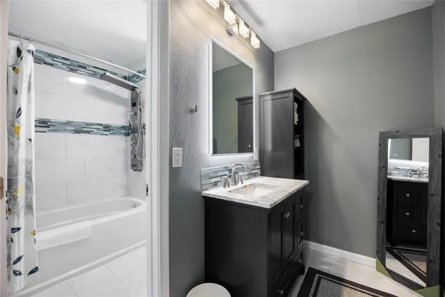 a bathroom with a granite countertop sink mirror and a bathtub