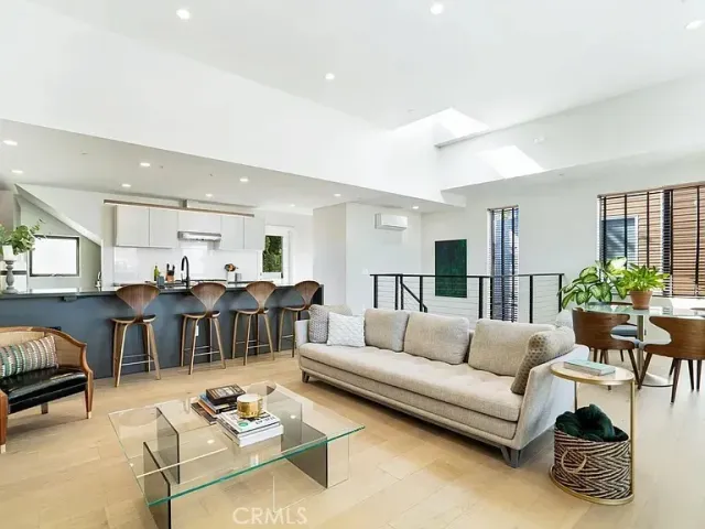 a living room with furniture a rug kitchen view and a table