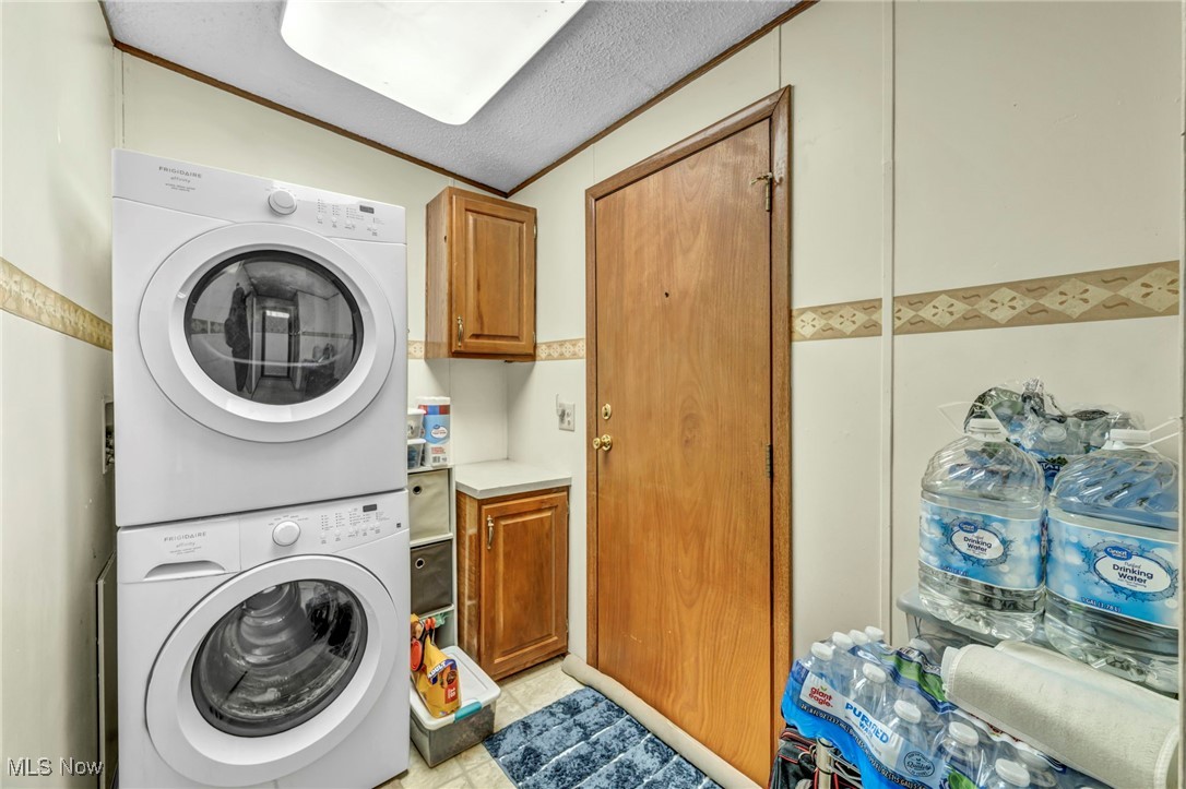27202 Cook Road, Unit 95 Olmsted Falls, OH 44138 - Photo 18 of 46 Laundry room with stacked washer and clothes dryer, cabinet space, a textured ceiling, and vaulted ceiling