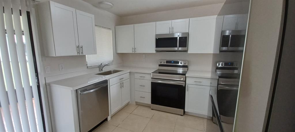 519 Southwest Sara Boulevard Port St. Lucie, FL 34953 - Photo 11 of 18 a kitchen with stainless steel appliances a stove microwave and refrigerator