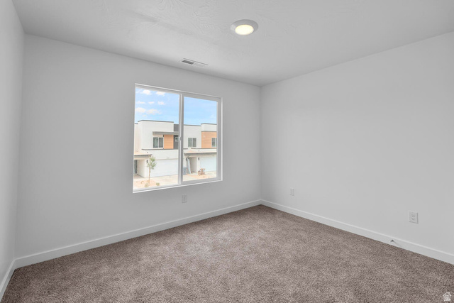 2133 Wolverine Way, Unit 2440 Washington, UT 84780 - Photo 15 of 39 Spacious room featuring neutral carpeting, white walls, a large window, a ceiling-mounted light fixture, and white baseboards