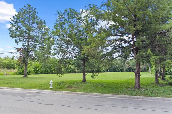 a view of a house with a big yard and large trees