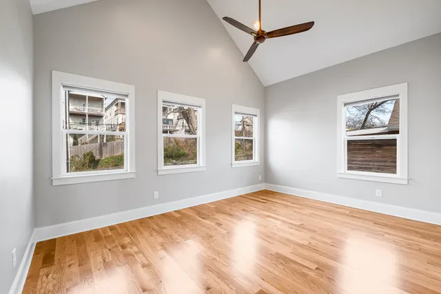 a view of empty room with wooden floor and fan