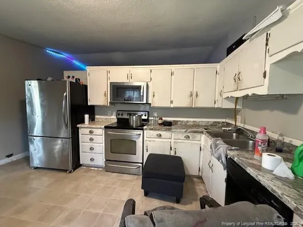 a kitchen with a sink white cabinets and stainless steel appliances
