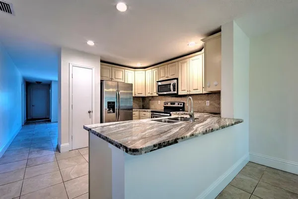 a kitchen with stainless steel appliances granite countertop a stove a sink and a refrigerator