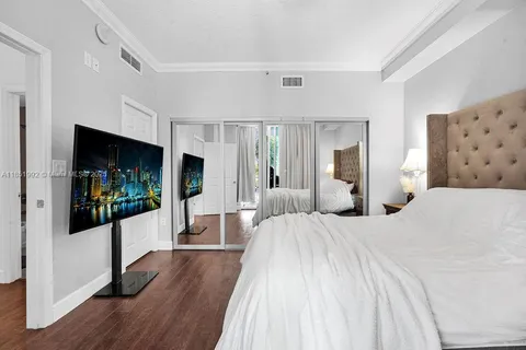 a bedroom with a large bed and a flat tv screen