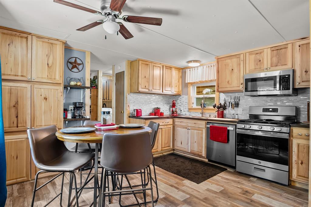 87 Ledbetter Road Mineral Wells, TX 76067 - Photo 7 of 22 a kitchen with stainless steel appliances a stove a sink dishwasher a dining table and chairs with wooden floor