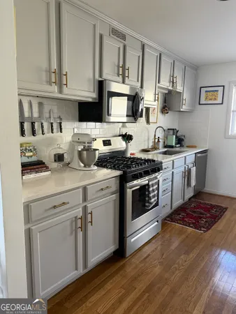 a kitchen with stainless steel appliances granite countertop a stove a sink and white cabinets
