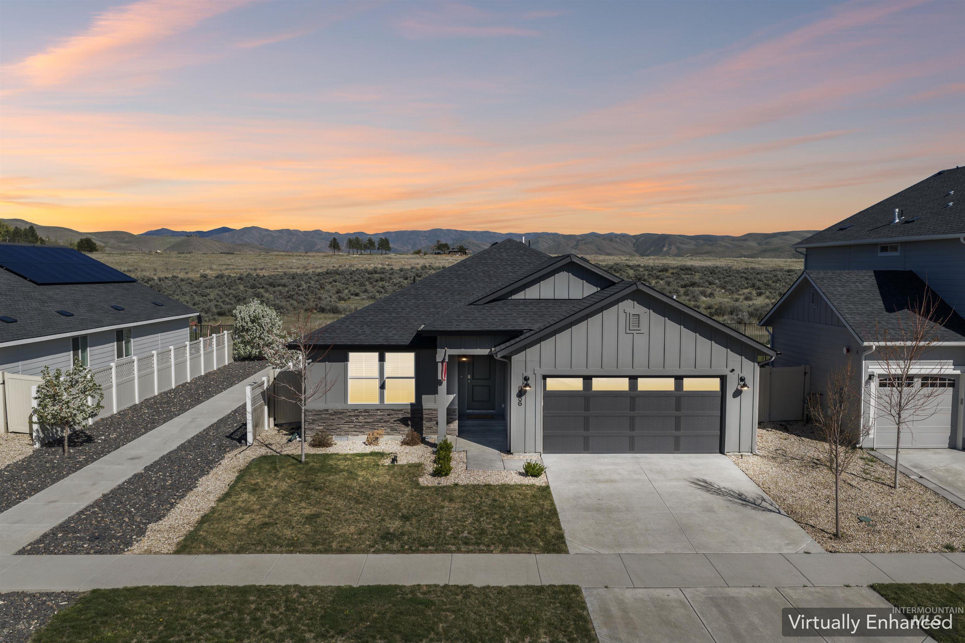 Modern farmhouse with board and batten siding, concrete driveway, an attached garage, a mountain view, and stone siding