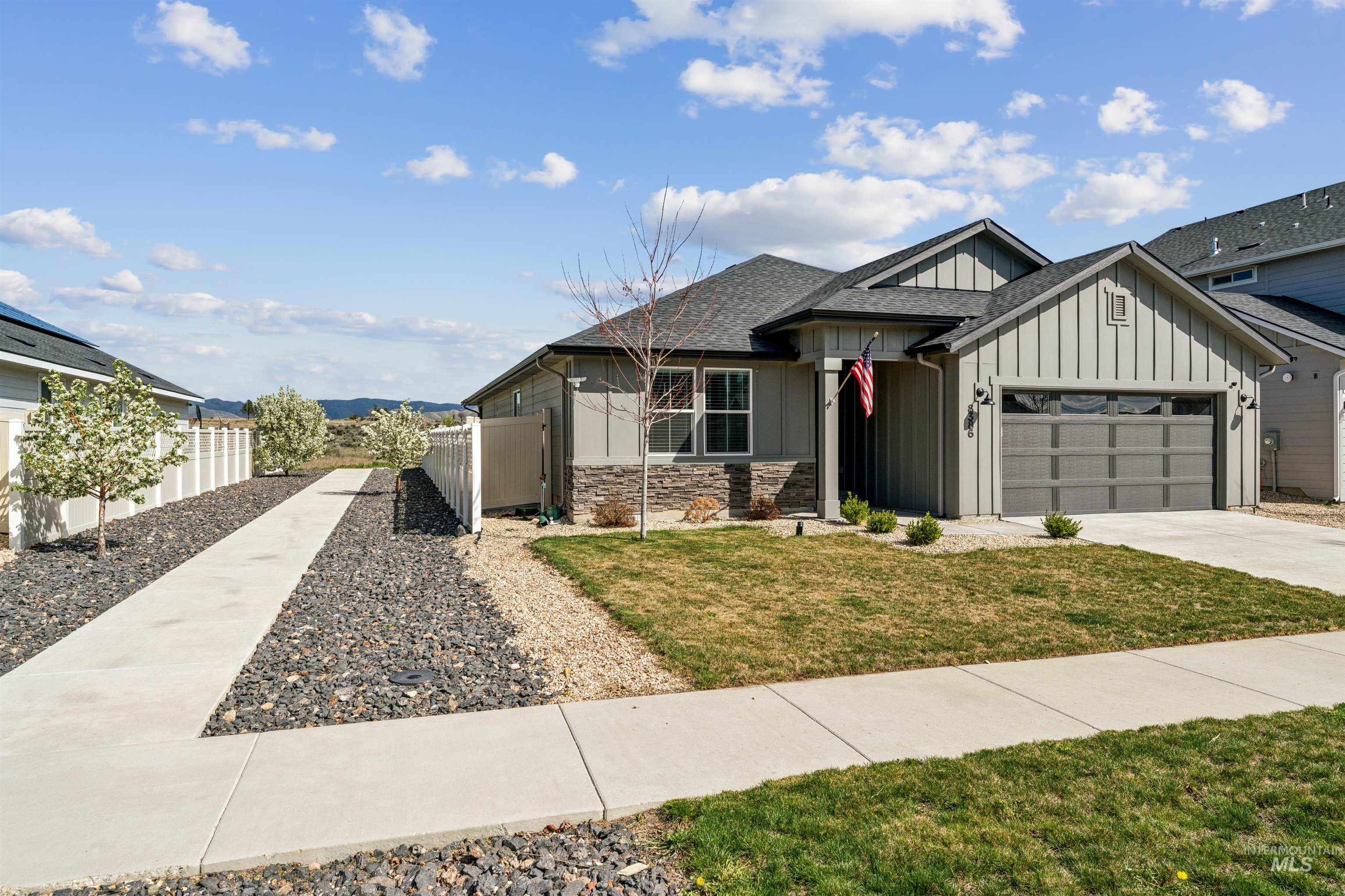 8386 South Bogus Rdg Avenue Boise, ID 83716 - Photo 49 of 50 View of front facade featuring board and batten siding, a garage, a shingled roof, driveway, and stone siding
