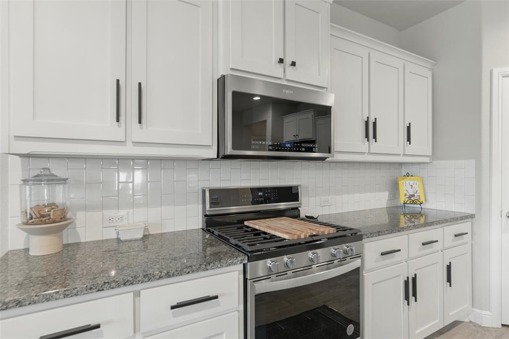 712 Finchley Drive Fort Worth, TX 76247 - Photo 9 of 37 a kitchen with granite countertop white cabinets and a stove